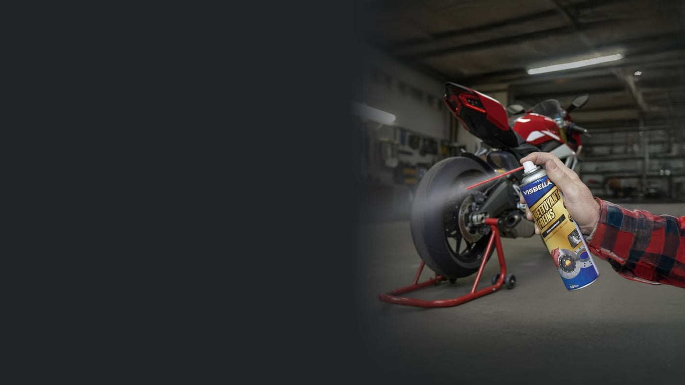 Un mécanicien pulvérise le nettoyant frein Visbella sur le disque d'une moto sportive pour un nettoyage en profondeur.
